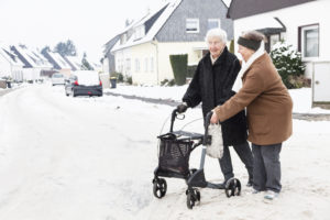 elderly woman with walker crossing a snowy street